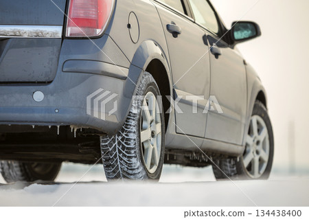 Close up of a car tire parked on snowy road on winter day. Transportation and safety concept. Close up of a car tire parked on snowy road on winter day. Transportation and safety concept. 134438400