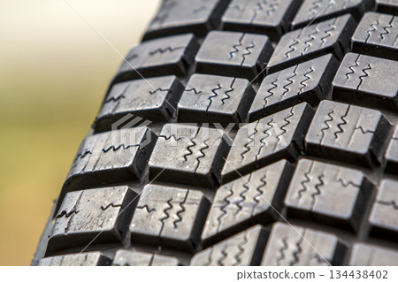 Close up detail of new black rubber car tire protector, selective focus, on copy space background. Close up detail of new black rubber car tire protector, selective focus, on copy space background. 134438402