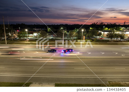 City street at night with police conducting a stop on a speeding car. Flashing red and blue lights reflect off nearby traffic in the USA. City street at night with police conducting a stop on a speeding car. Flashing red and blue lights reflect off nearby traffic in the USA. 134438405