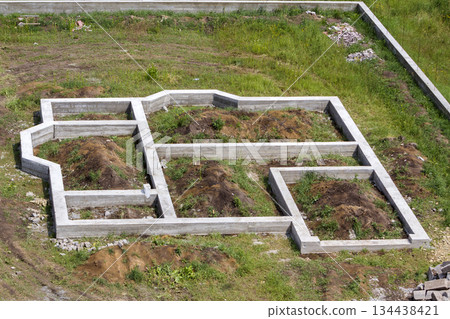 Building site in green field. Trenches dug in ground and filled with cement as foundation for future house and fence around territory. Building, construction, investment and real property concept. 134438421
