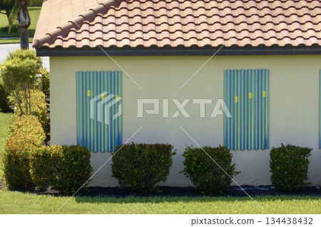 Boarded up windows with steel storm shutters for hurricane protection of residential house. Protective measures before natural disaster in Florida 134438432