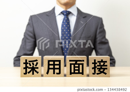 一塊寫著「求職面試」字樣的磚塊和一個商人 一塊寫著「求職面試」字樣的磚塊和一個商人 134438492