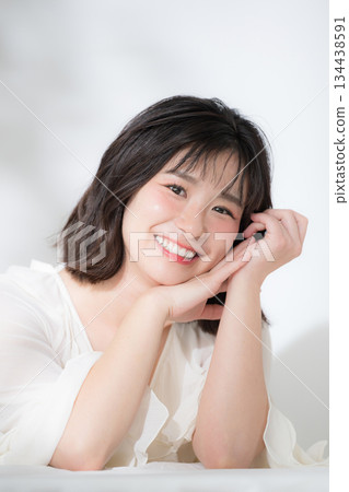 一張美麗的圖片，畫面中一位快樂、年輕、氣質柔和的女性，膚色白皙，神采奕奕，面帶微笑，一手托著下巴（下巴擱置）。 134438591