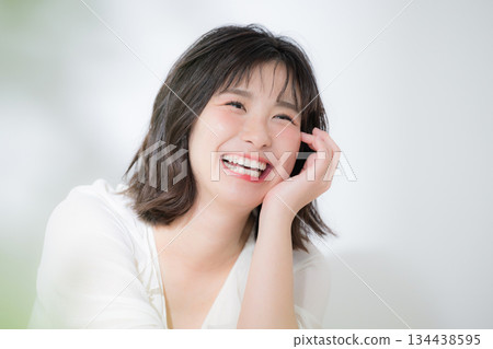 A beauty image of a happy, young, soothing woman with a clear complexion and a sense of euphoria, smiling with her hand on her chin (chin resting) 134438595