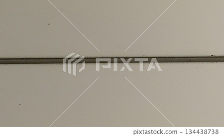 A close-up of a neutral-toned wall featuring a subtle, thin line across it. This texture serves as a versatile backdrop for graphic design, text mockups, and creative visual compositions. 134438738