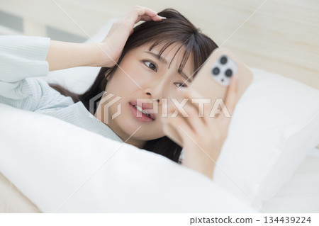 A woman watching a smartphone in bed 134439224