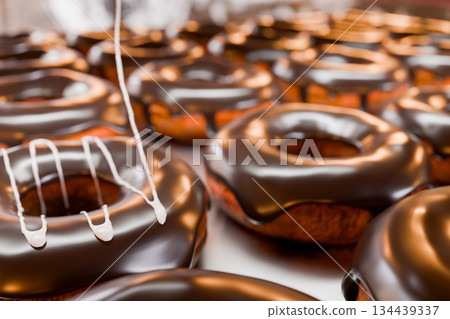 將白色液態奶油淋在擺放在托盤上的甜甜圈上。 134439337