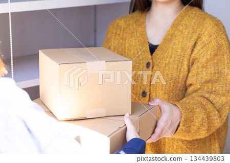 A woman receiving a package from a delivery person A woman receiving a package from a delivery person 134439803