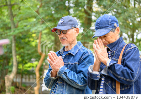 一對身穿牛仔服的中年夫婦在神龕前祈禱。 一對身穿牛仔服的中年夫婦在神龕前祈禱。 134439879
