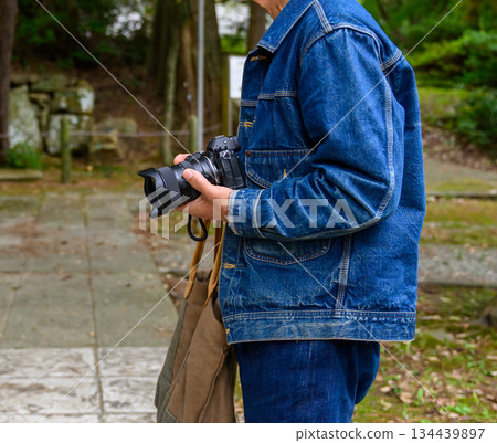 一位老人在神社裡拿著相機。 134439897