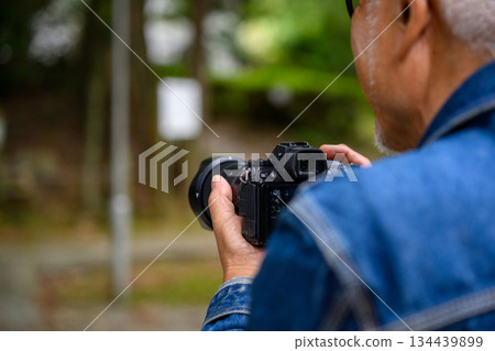 Rear view of a senior man holding a camera 134439899