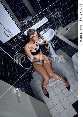 Drunk young woman sleeping on the toilet in a restroom 134439971