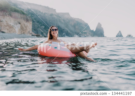 Woman, sea, vacation. Young woman floats on donut ring in the sea enjoying a relaxing summer holiday. Woman, sea, vacation. Young woman floats on donut ring in the sea enjoying a relaxing summer holiday. 134441197