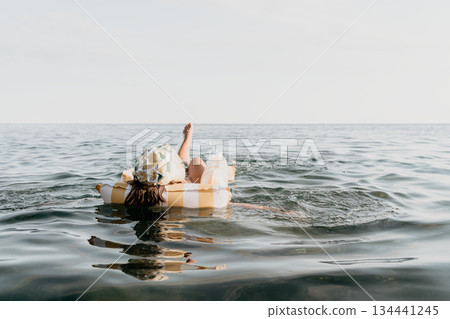 Woman, Inflatable Raft, Ocean - A woman relaxes on an inflatable raft in the ocean. Woman, Inflatable Raft, Ocean - A woman relaxes on an inflatable raft in the ocean. 134441245
