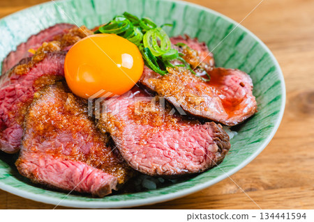Roast beef bowl topped with egg yolk 134441594