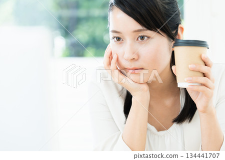 Woman drinking coffee while working Woman drinking coffee while working 134441707