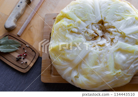 Process of making homemade stuffed cabbage rolls with minced meat, rice and spices in a cozy home kitchen. Traditional comfort food preparation, step by step cooking concept. 134443510