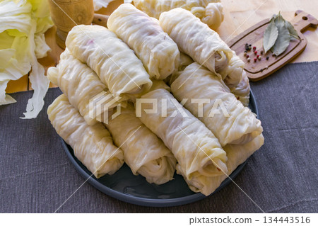 Process of making homemade stuffed cabbage rolls with minced meat, rice and spices in a cozy home kitchen. Traditional comfort food preparation, step by step cooking concept. 134443516
