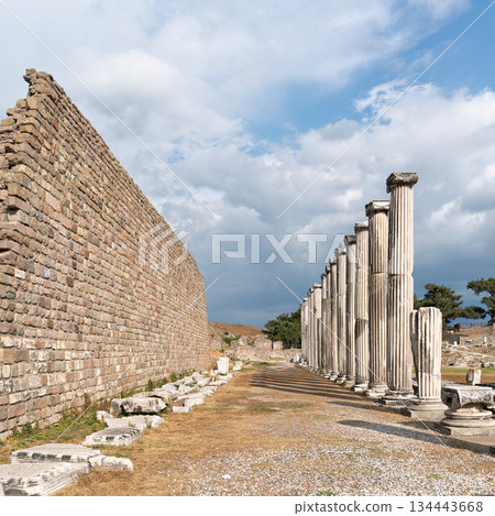 Ancient Roman columns and stone wall of the Sacred Way to Asklepion, Bergama, Turkey, under cloudy sky. Ancient Roman columns and stone wall of the Sacred Way to Asklepion, Bergama, Turkey, under cloudy sky. 134443668
