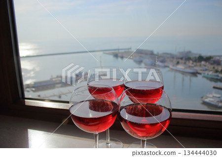 Red wine glasses by window overlooking harbor 134444030