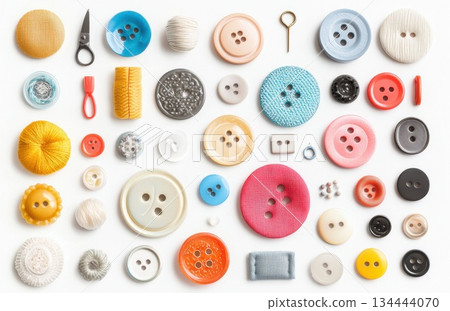 Colorful sewing accessories arranged on white surface, featuring buttons, thread spools, scissors creating neat craft workshop composition 134444070