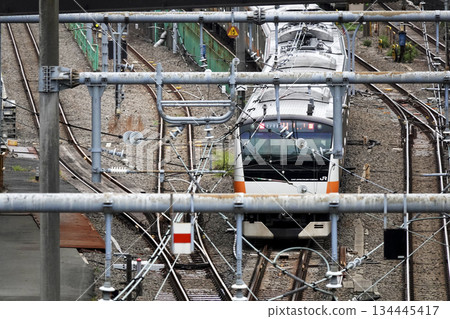 火車的上部受電弓和架設在鐵路線上方高架人行天橋上的架空電線 火車的上部受電弓和架設在鐵路線上方高架人行天橋上的架空電線 134445417