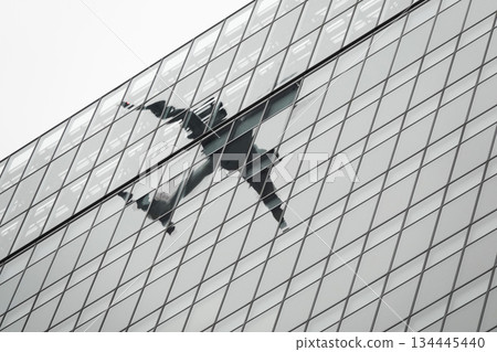 Passenger plane reflected in the glass of a building Passenger plane reflected in the glass of a building 134445440