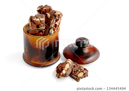 Sweet nutty caramel bars covered with chocolate in a wooden bowl. 134445494