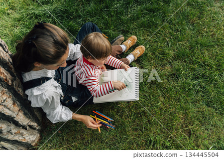 Mother and Toddler Drawing Together in a Summer Park. Parenting and Childhood Development Concept Mother and Toddler Drawing Together in a Summer Park. Parenting and Childhood Development Concept 134445504