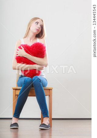 Sad unhappy woman holding red heart pillow 134445543