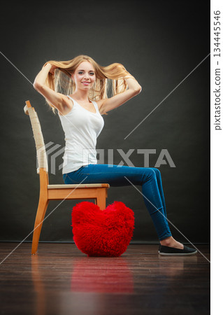 Happy woman with heart shaped pillow on floor 134445546