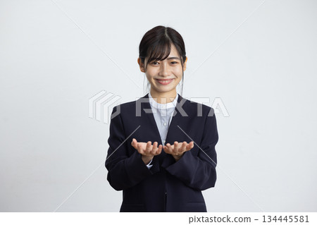 A young businesswoman smiling with her hands in front of her chest in front of a white wall 134445581