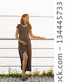 Elegant Pregnant Woman Relaxing By Waterfront At Sunset 134445733