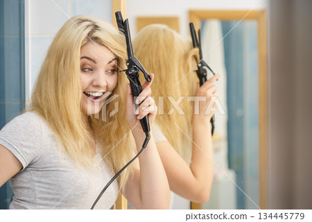 Woman using hair curler Woman using hair curler 134445779