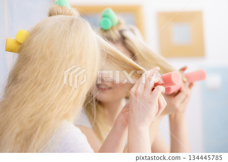 Blonde woman using hair rollers 134445785