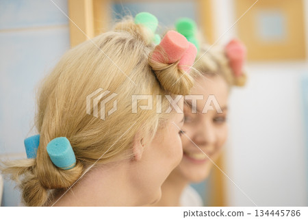 Blonde woman using hair rollers 134445786