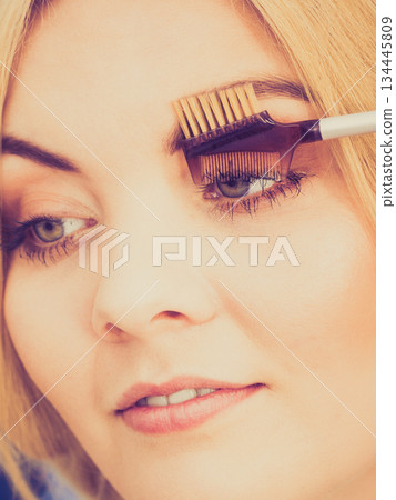 Woman brushing her eyelashes Woman brushing her eyelashes 134445809