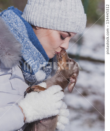 Woman playing with dog during winter Woman playing with dog during winter 134445812
