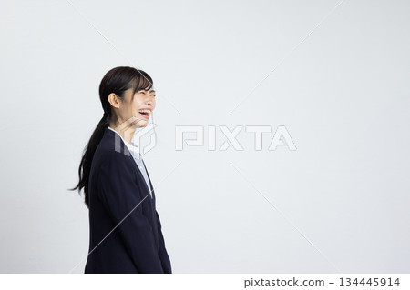 Profile of a young businesswoman smiling in front of a white wall Profile of a young businesswoman smiling in front of a white wall 134445914