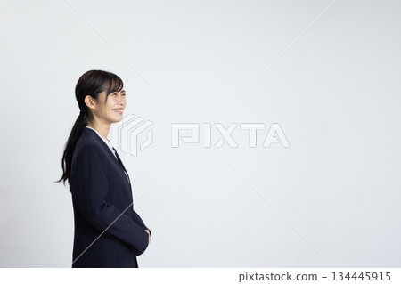 Profile of a young businesswoman smiling in front of a white wall Profile of a young businesswoman smiling in front of a white wall 134445915