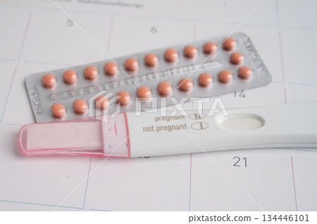 Pregnancy test and condom for female on calendar, ovulation day. 134446101