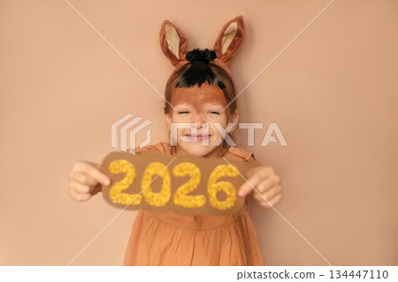 Funny laughing child in a fire horse costume shows the numbers of the new year 2026 Funny laughing child in a fire horse costume shows the numbers of the new year 2026 134447110
