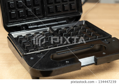 The waffle iron is covered with oil and preheated, ready for baking waffles The waffle iron is covered with oil and preheated, ready for baking waffles 134447239