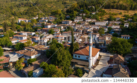 Aerial view of Sirince village in Turkey with traditional houses and mosque surrounded by green hills. Historic rural settlement, cultural heritage and popular travel destination. 134448330