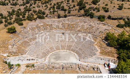 Aerial view of an ancient Greek amphitheater ruins in Bodrum, Turkey. Historic stone theater surrounded by dry landscape, archaeological site and cultural heritage landmark. Aerial view of an ancient Greek amphitheater ruins in Bodrum, Turkey. Historic stone theater surrounded by dry landscape, archaeological site and cultural heritage landmark. 134448334