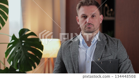 Psychologist man in clinic office professional portrait with smile and holding clipboard for patient to visit psychologist. Mental health and psychology. Psychologist man in clinic office professional portrait with smile and holding clipboard for patient to visit psychologist. Mental health and psychology. 134448508