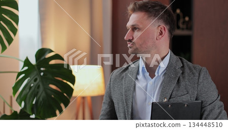 Psychologist man in clinic office professional portrait with smile and holding clipboard for patient to visit psychologist. Mental health and psychology. Psychologist man in clinic office professional portrait with smile and holding clipboard for patient to visit psychologist. Mental health and psychology. 134448510