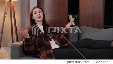 Woman lies on couch sharing personal life problems in therapy room. Man psychologists takes notes in notebook documenting key insights during conversation. Woman lies on couch sharing personal life problems in therapy room. Man psychologists takes notes in notebook documenting key insights during conversation. 134448538