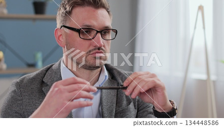 Man psychologist sits in office and listens attentively, holds pen and notebook. Therapist on therapy session. Man psychologist sits in office and listens attentively, holds pen and notebook. Therapist on therapy session. 134448586