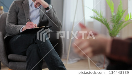 Man therapist, notes and patient in consultation for mental health, discussion and recovery support for anxiety. Therapy, psychologist and hands of person for counseling. Man therapist, notes and patient in consultation for mental health, discussion and recovery support for anxiety. Therapy, psychologist and hands of person for counseling. 134448589